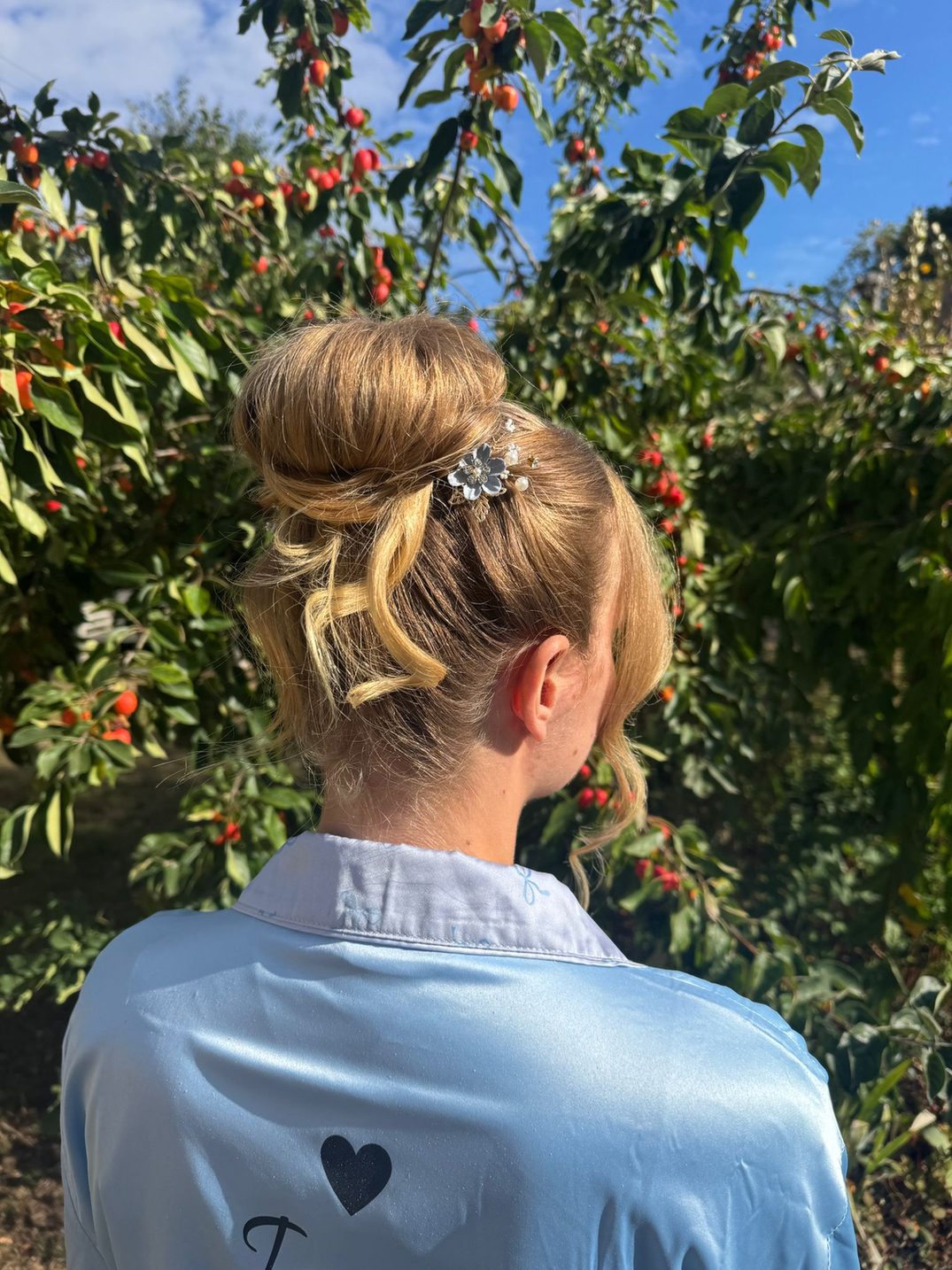 Outdoor bridal updo hairstyle with floral pin by Lucent Hair