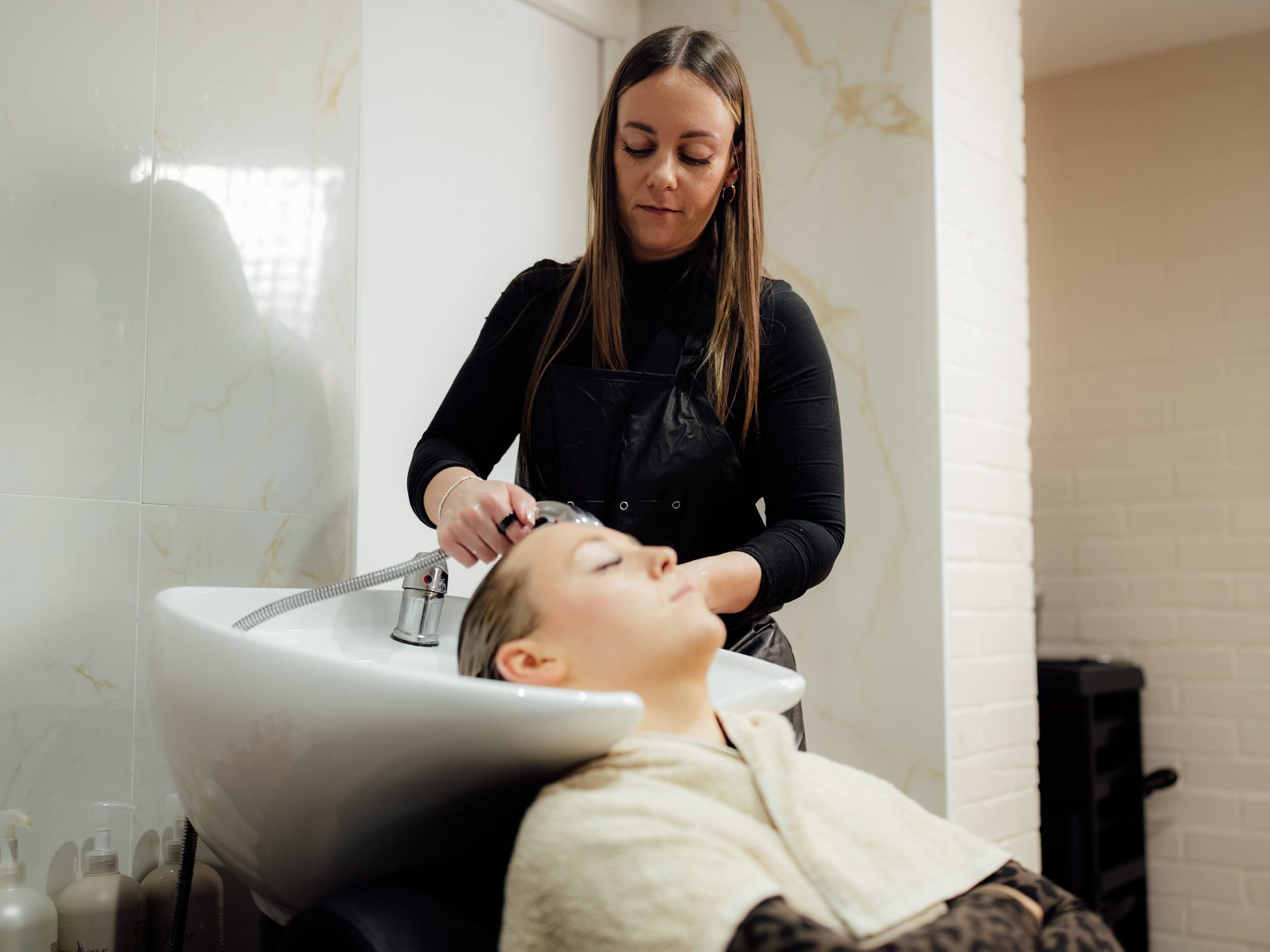 Rebecca washing a client's hair at the basin at Amica Lounge in Sawtry